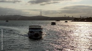Camera tilts down and follows an Istanbul ferry from the Bosporus at sunrise.