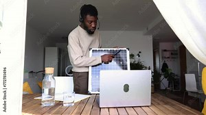 Remote Solar Technology Consultant Giving an Online Presentation. A professional African American consultant conducts a remote presentation, pointing out features on a solar panel, from his home offic