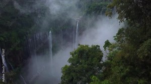 Aerial static shot: Fly cam open view to Tumpak Sewu waterfall in clouds and mist, Java island, Indonesia