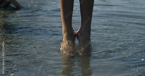 Child legs jumping in super slow-motion 800 fps with ripples of water flowing, little girl bouncing up captured with high speed camera, contact with nature