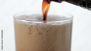 Slowly pouring Irish stout out of a bottle into a glass