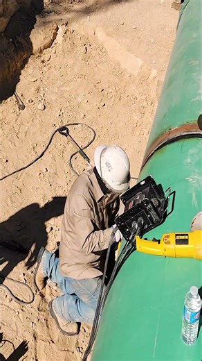 Cleaning up excess welding with a grinder after welding a pipe