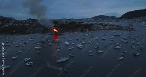 Extremely beautiful, turning aerial time lapse that reveals the biggest bonfire event on Earth while small boats and a sailing cruise ship is gathering around it near Alesund, Norway at dusk.