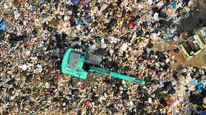 From above, a landfill section reveals the enormity of waste management. An excavator and dump truck stand out amidst a sea of mixed waste, illustrating the scale of the task at hand. 4K.