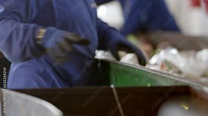 Workers wearing PPE selecting and sorting plastic waste for recycling