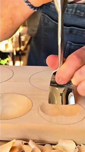 hollowing out smooth circular indentations in a flat wooden board using a sharp curved metal gouge