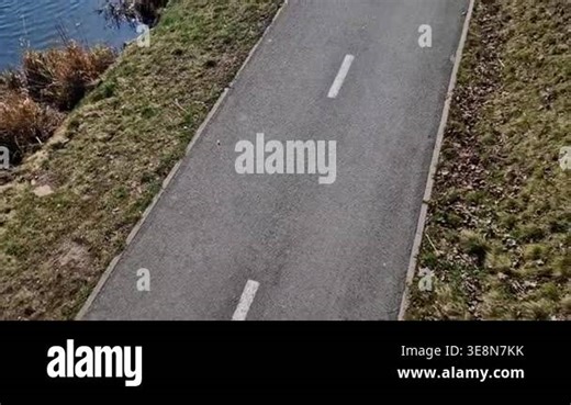 bike path right next to meanders encourages cyclists to continue along water, shared-use path or cycleway running alongside river or canal, given embankment.dashed white line indicates that path is intended for two-way traffic cyclists or pedestrian Stock Video Footage - Alamy