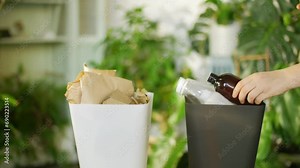 waste sorting at home. close up video female hand putting plastic cosmetic bottle and paper into recycle bins. colorful trash bins for sorting waste in the kitchen. recycling, zero waste