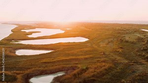 Aerial view of lakes and islets near Black Sea on backdrop of summer sunset. Stunning flight over beautiful places in reserve of Crimea, Ukraine. Top view of wonderful nature, water among trees grass.