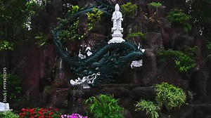 Buddhist statue and dragon fountain in a garden at a pagoda in Vietnam in Asia