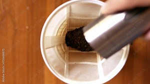 Top view of hand pour ground coffee over paper filter in clever coffee dripper before pouring water from drip kettle. 4k video