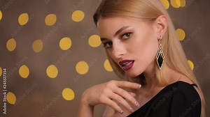 Pretty attractive fashion model with beautiful blonde hair and nice face posing in yellow lights bokeh, studio shot, slow motion