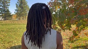 Black person with henna dyed dreadlocks standing outside