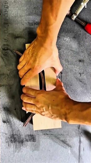 Fitting curved strip into wooden groove with clamp nearby on textured workbench