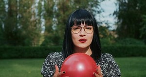 a joyful woman plays with balloons, imitating the reliability of condoms during sex, they will withstand any test and load.