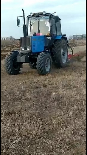 Blue Tractor Tilling Soil in Open Field