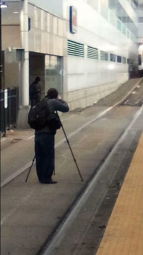 man stands in front of on coming train