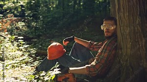 Male logger sitting on ground taking a break. RAW video record.
