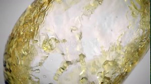 Slow motion(ultra slow motion) shot of yellow liquid flow . Yellow liquid swirls in a transparent glass container. Shot on Phantom High speed camera. The liquid resembles wine/oil/yellow liquid.