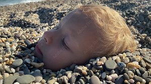 Children playing on the beach. Older brother burying little boy in sand. Children summer vacation. Yevpatoriya, Crimea, Russia 2024 Stock Video