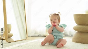 Cute baby girl playing with first toothbrush in domestic room.