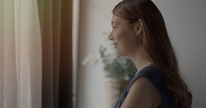 Woman opening curtains in early morning