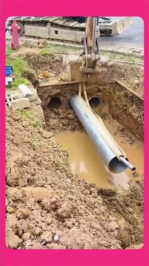 Using an excavator to help install the metal pipe into the water drainage channel.