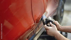 Car body repair. Car dent removal techniques, a auto body repair man removing auto body dent by the mechanic. Garage mechanic removing paint with the Angle Grinder before standing the work.
