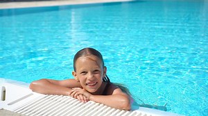 Adorable little girl swimming at outdoor swimming pool