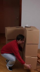 A man bending over to pick up a stack of boxes