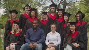 Closeup of carefree multiracial diverse graduates in gowns and mortarboards with cheerful multiethnic professors posing for picture together, showing positive vibes after receiving university diploma.