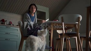 Cheerful woman eating food and talking with her dog at breakfast