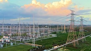 Aerial footage of high voltage power tower in substation. Transmission power line. Electricity pylons and sky clouds background at sunset.