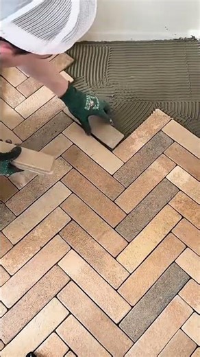 installing brick floor tiles in a herringbone pattern with precision adhesive and manual skills