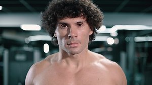 clip-1078664084-young-athletic-man-lifts-weights-gym-raising