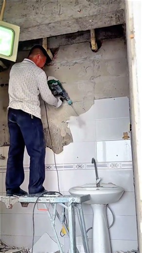 Worker Using Demolition Hammer to Remove Bathroom Wall Tiles for Renovation