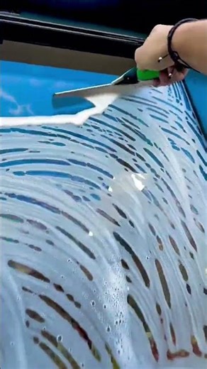 cleaning building window glass using squeegee tool and soap evenly in the outdoor area surface