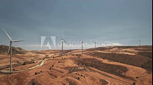 Windmills rotate produce electricity in desert area in Larnaca, Cyprus. Modern white wind turbines use planet natural resources for alternative energy production. Environment save. Zoom out view.