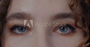 Close-up of beautiful female eyes looking at camera blinking expressing no emotion. Face expression and attractive people concept.