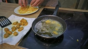 Cook throws battered mussels in a pan to fry them. Medium shot