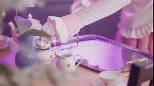 Pink maid with gloves at home prepare table with retro tea cups close-up 4K