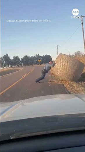 Missouri State Highway Patrol trooper shows off strength as he pushes a hay bale off a road