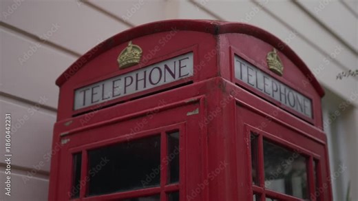 Close-up of a red London telephone box showing exterior design details. Iconic British street feature in an urban environment. Travel, culture, heritage, and city-themed visuals.