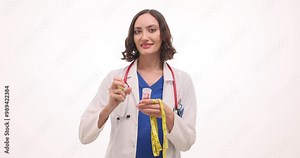 Woman doctor in white robe shows bottle with capsules and measuring tape against white. Medic with stethoscope presents supplements for diet