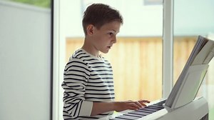 clip-1030418177-handsome-teenage-boy-playing-piano-home