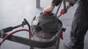 Close-up - cleaning with a construction vacuum cleaner. Removal of dust and dirt. A worker vacuums a concrete floor. Worker washes the floor with a vacuum cleaner. Worker with an industrial vacuum