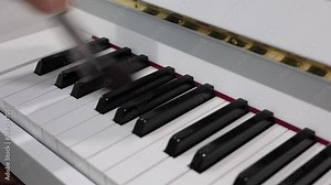Dusting dust off piano keys with a brush, cleaning piano keys, dusting piano keys