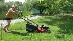 Farmer boy cutting grass with lawnmower in sustainable organic garden.