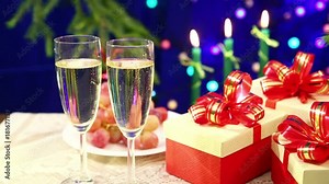 Bubbles spin in glasses with Shompansky close-up on the background of a table with boxes of gifts, burning candles and herders blurry bokeh. Shooting the paralax with dolly from right to left