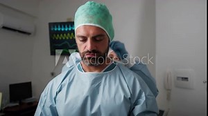 Assistant helps the surgeon to don the sterile gown